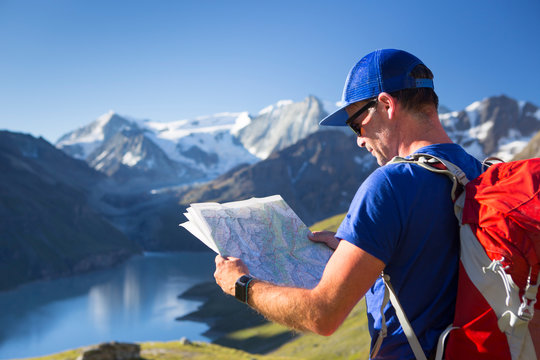 A male hiker is looking at a map to find his route through the mountains