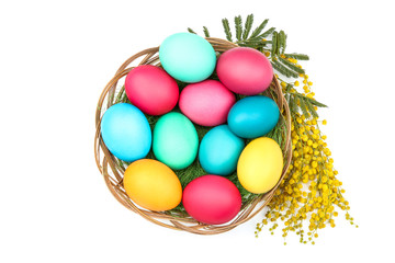 Easter eggs in basket with flowers isolated on white background