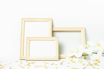 White Phalaenopsis orchid flowers, wooden photo frames, golden stars confetti on white background. Branch of Tropical flower. Holiday, Women's Day flat lay. Interior details Layout for design Mockup