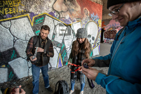 Friends passing out headlamps in front of graffiti-covered wall, Portland, Maine, USA