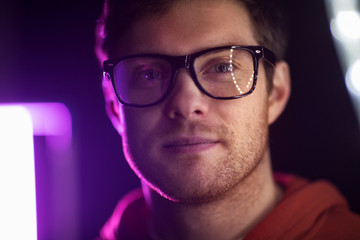 vision, eyewear and people concept - portrait of smiling young man in glasses over ultra violet...