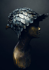 Closeup of bronze head of mannequin in decorated bronze head-wear bird head shaped, dark studio...