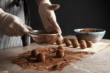 Fototapeta na wymiar Woman preparing tasty chocolate truffles at table, closeup