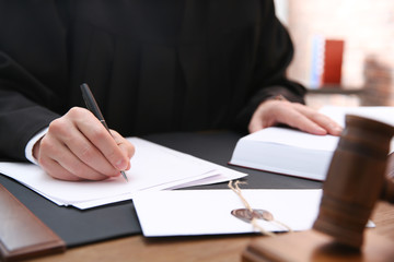 Obraz premium Judge working with papers at table in office, closeup. Law and justice concept
