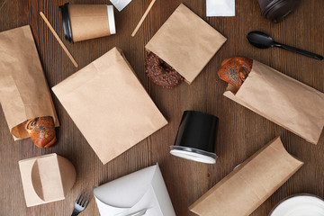 Flat lay composition with paper bags and different takeaway items on wooden background. Space for...