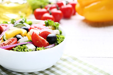 Vegetable salad in bowl with napkin on wooden table