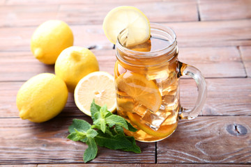 Ice tea in glass jar with lemon and mint leafs on wooden table