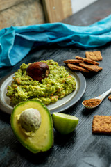 green, naturally made traditional guacamole surrounded by fresh ingredients and nachos