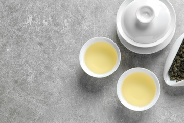 Flat lay composition with cups of Tie Guan Yin oolong tea and space for text on grey background - obrazy, fototapety, plakaty