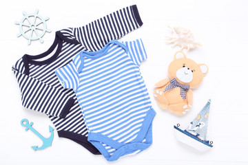 Baby clothes with soft toy and sea decor on white background