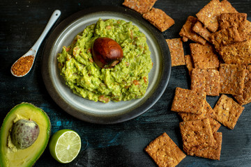 green, naturally made traditional guacamole surrounded by fresh ingredients and nachos