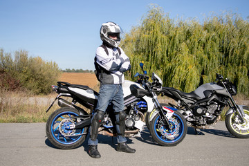 The motorcyclist in helmet on a motorcycle. Journey to a motorcycle. Motorcyclist stands on the road