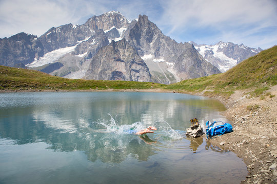 A male hiker is taking a bath in a mountain lake near Courmayeur in the Italian Alps, with Mont Blanc in the back ground. 
