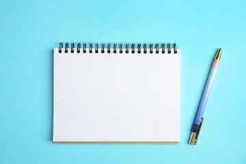 Empty notebook and pen on color background, top view