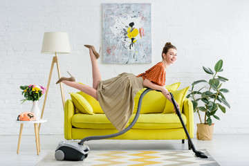 elegant smiling young woman levitating in air and holding vacuum cleaner