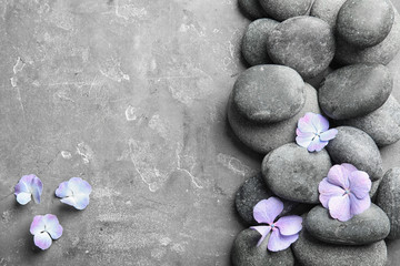 Fototapeta na wymiar Zen stones and exotic flowers on grey background, top view with space for text