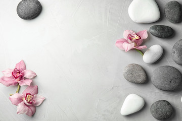 Pierres zen et fleurs exotiques sur fond gris, vue de dessus avec un espace pour le texte