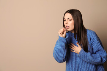 Beautiful young woman coughing against color background. Space for text