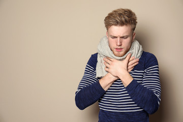 Handsome young man coughing against color background. Space for text