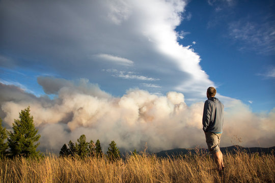 Man watching Lolo Peak Fire blow up in heavy winds from top of Blue Mountain near Missoula, Montana, USA