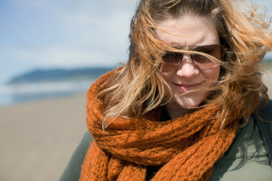 Portrait of woman with windblown hair wrapped in orange scarf at Cannon Beach, Oregon, USA.