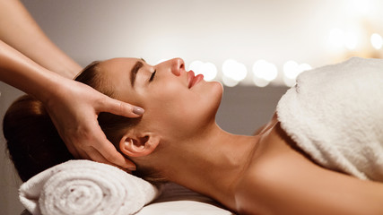 Obraz na płótnie Canvas Young woman receiving professional head massage at spa