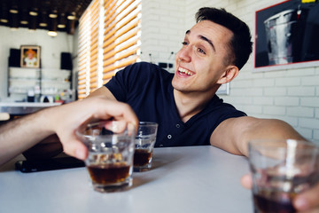 Young man drunk at bar drinking alcohol whiskey smiling