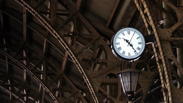 Clock on the old railway station among the metal structures.