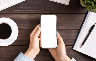 Woman using blank smartphone on workplace desk