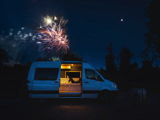 Woman reading in van with fireworks in background