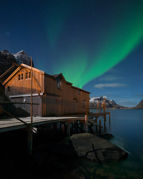 Aurora Borealis shine in sky over cabin, Norway