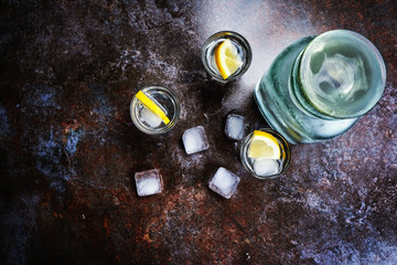 Vodka in glasses with lemon and ice. On the black stone table. Copyspace.