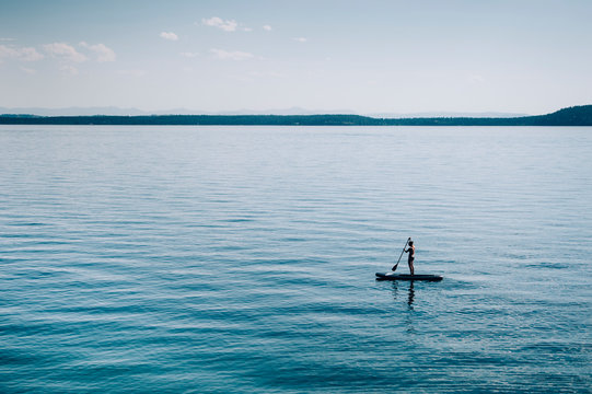 Woman standing up paddle boarder paddling on Flathead Lake, Montana, USA