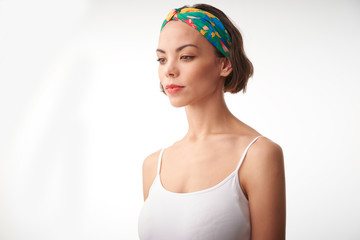 Half profile portrait shot of young woman standing at isolated white background and thinking