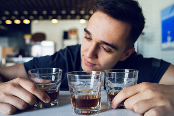 Young man drunk at cafe bar holding glass of alcohol whiskey brandy
