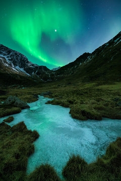 Aurora Borealis shine in sky over frozen ice river, Norway