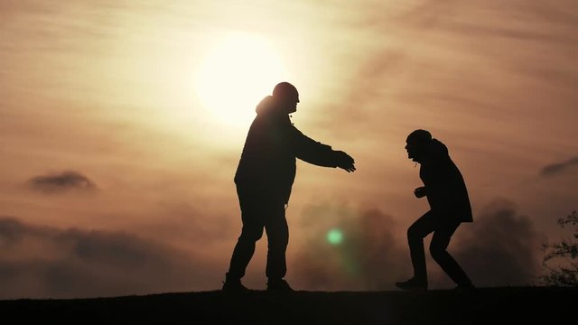 Happy father catching his jumping son in a field at dark sunset in spring in slo-mo  