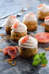 Homemade healthy sugar free sweets. Dried fruits muffins with cream cheese and blood orange icing on dark background