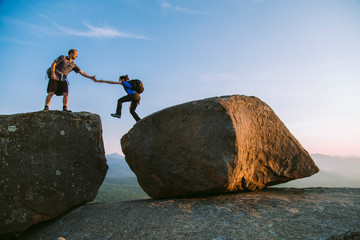 Man helping woman across boulder, Pitchoff?Mountain, Adirondack Mountains, New York State, USA