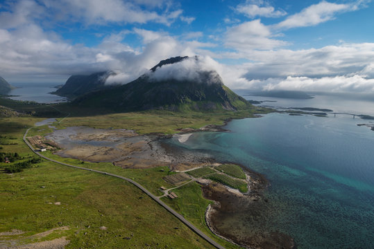 Highway leading through flatland near mountain peak and coastline