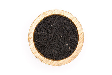 Lot of whole black cumin seeds with wooden bowl flatlay isolated on white background