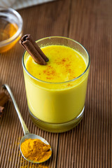 Turmeric Golden Milk. Healthy drink made with turmeric honey and cinnamon. Remedy for many diseases. Rustic wooden background.