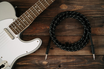 Fototapeta premium Guitar electric rock background. Cable jack on wooden table, top view