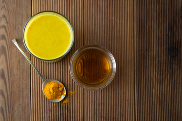 Turmeric Golden Milk. Healthy drink made with turmeric and honey. Remedy for many diseases. Rustic wooden background.