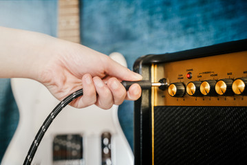 Guitar electric amplifier. Rock overdrive effect. Hand is plugging a cable into amp jack. Max...