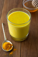 Turmeric Golden Milk. Healthy drink made with turmeric and honey. Remedy for many diseases. Rustic wooden background.