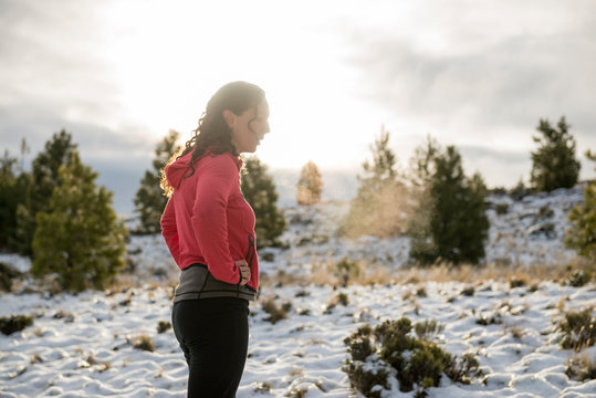 Woman takes a breather in a snowy field in Patagonia, showered with evening light.