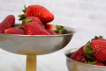 Bright ripe strawberry in a metal cups on a light background.