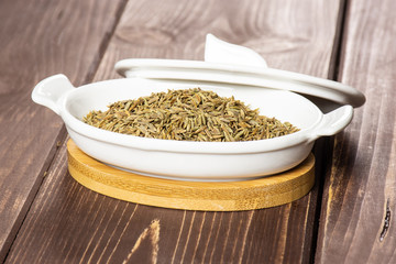 Lot of whole roman caraway seeds in a ceramic stewpan on brown wood