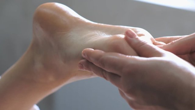Professional massage therapist does a foot massage to a young woman.